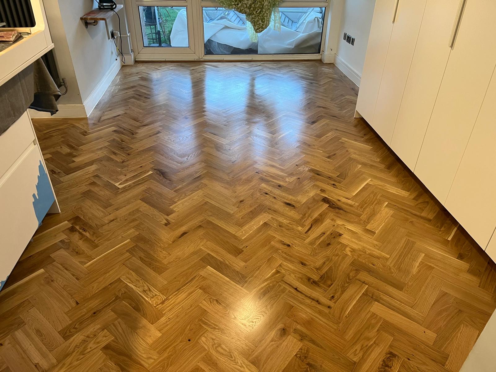 Parquet Floor Restoration in Hounslow showing a fully refinished honey-toned oak herringbone parquet wood floor in a bright living space.