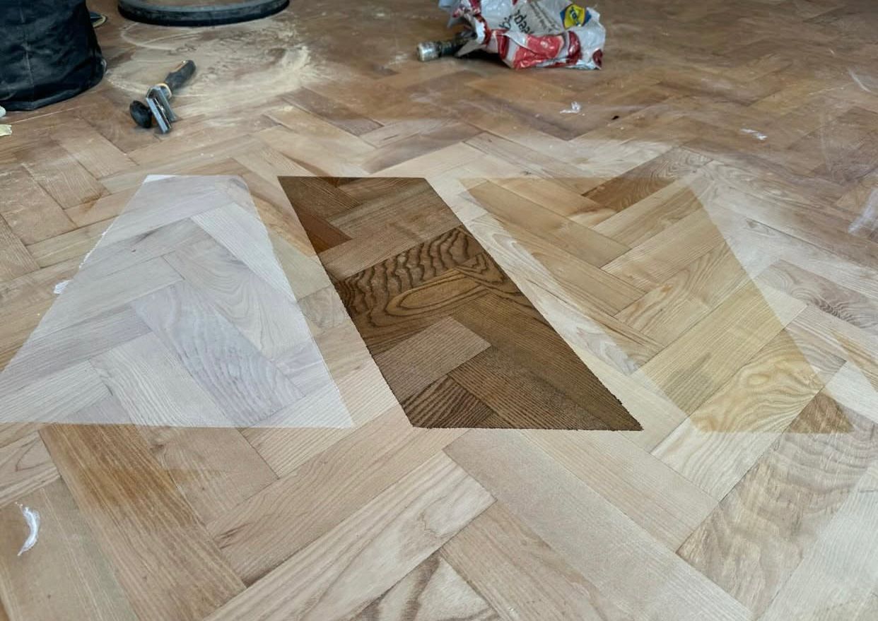 Parquet Floor Restoration in Hounslow showing colour samples on a sanded herringbone oak parquet wood floor to choose the final finish.