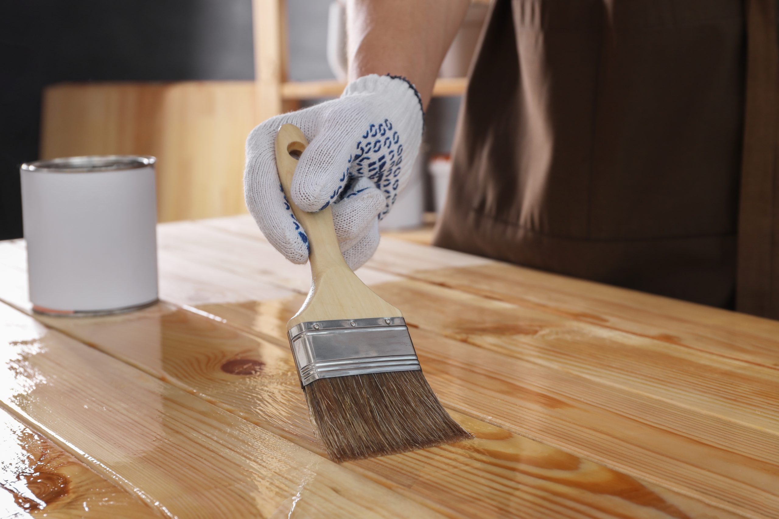 Worktop refinishing in Hounslow – tradesperson applying clear finish to a solid pine wood kitchen worktop and matching pine floor for a smooth, protected surface.