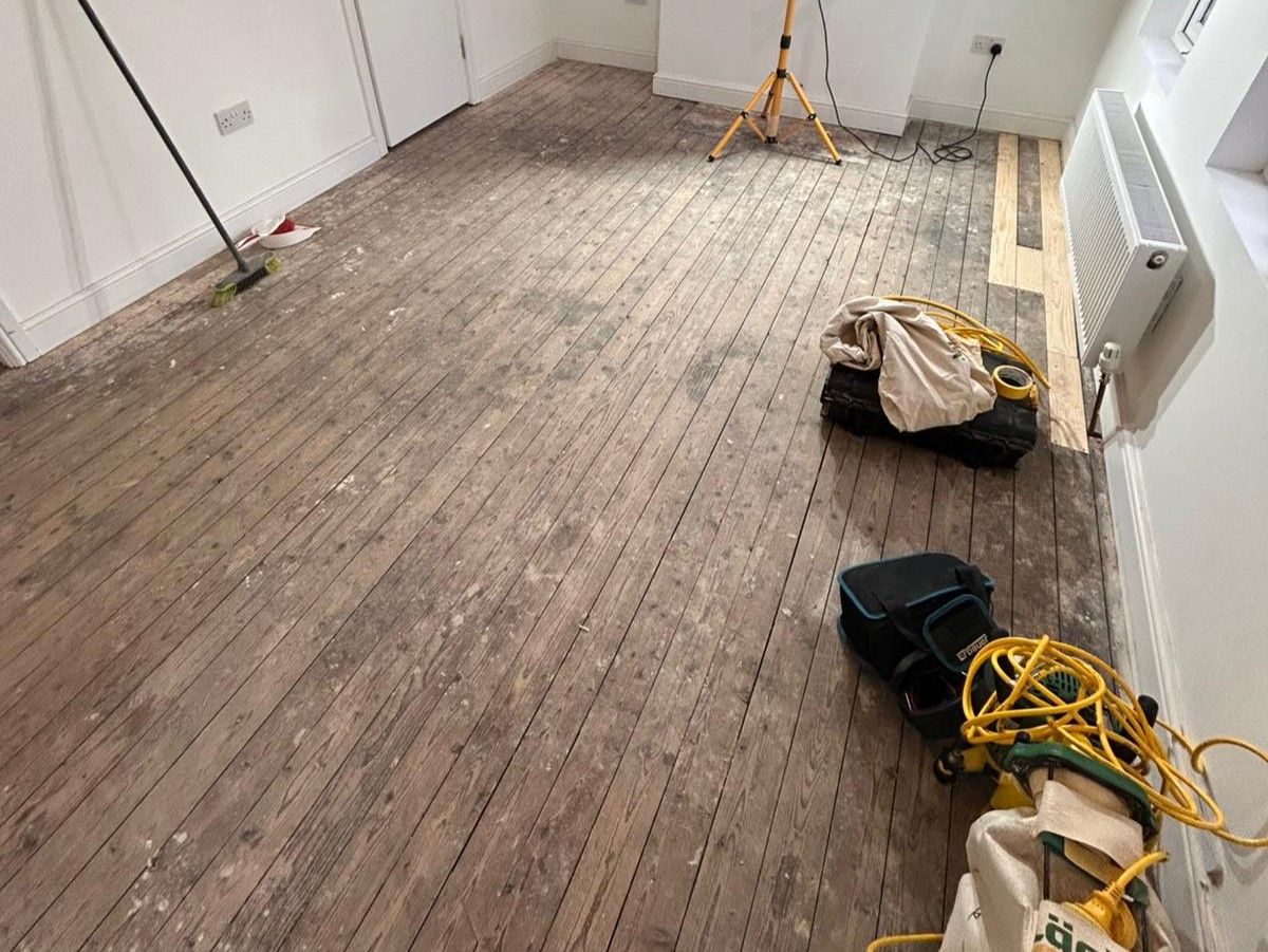 Wood Floor Sanding in Hounslow on an original narrow pine softwood floorboard room, showing preparation work and worn boards ready for sanding and refinishing.