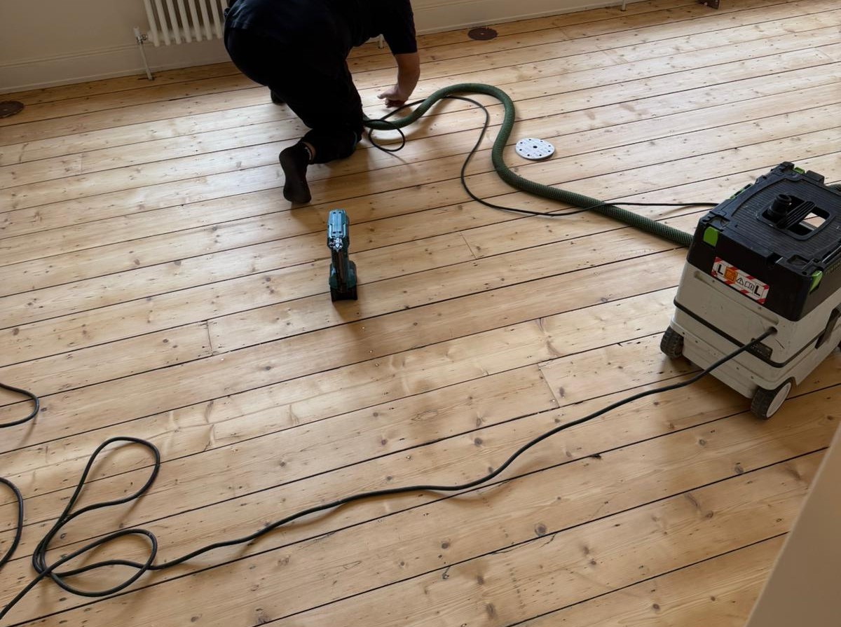 Wood Floor Sanding in Hounslow on Victorian pine softwood floorboards, showing detailed edge sanding and dust extraction during timber floor restoration.